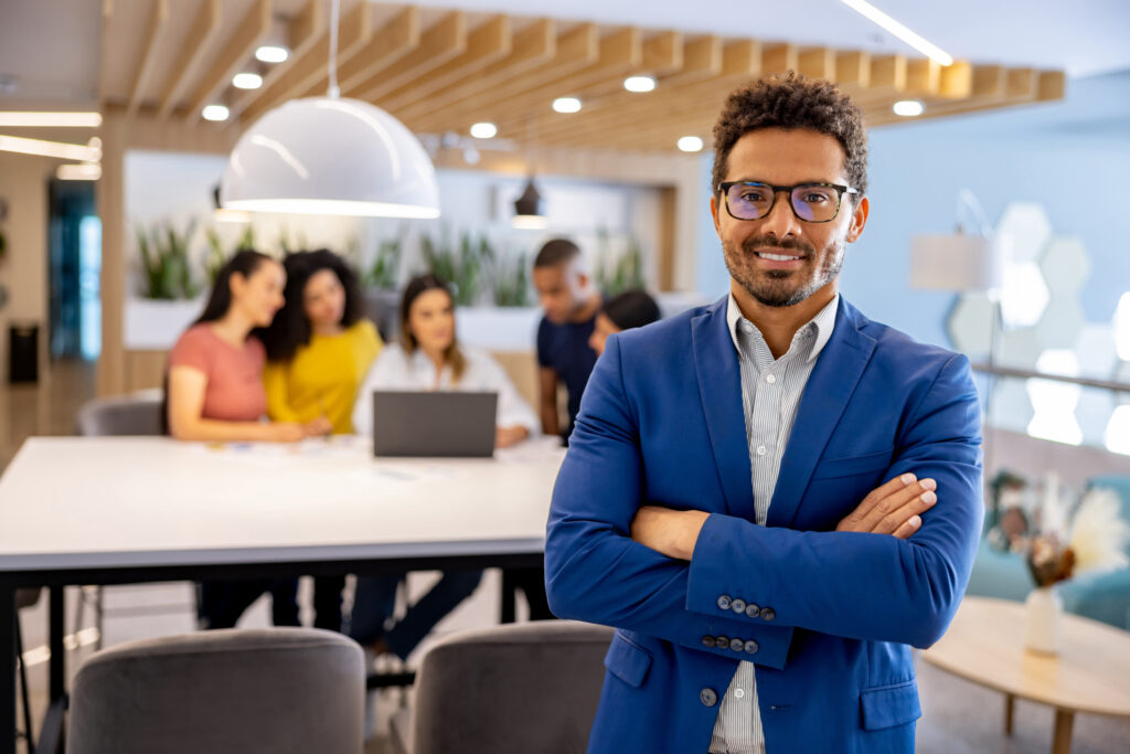 Portrait of a business man working at a coworking office and looking at the camera while a group works at the background