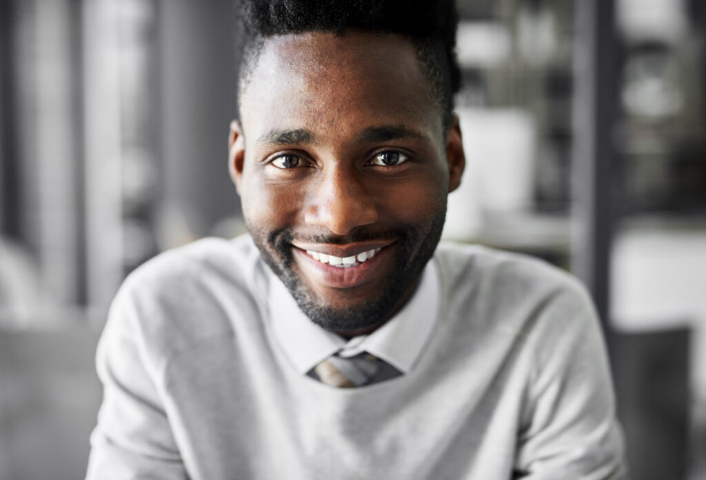 Portrait of a smiling young businessman sitting at a desk in an office