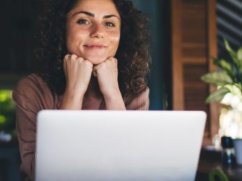 A woman smiling in front of her laptop