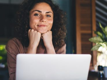 A woman smiling in front of her laptop